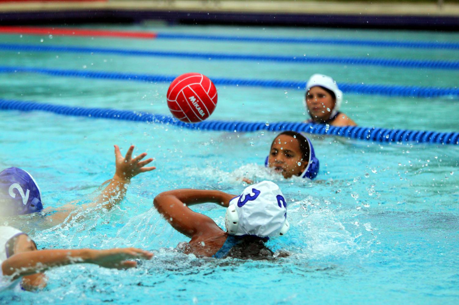 Group of young teenagers playing water polo in large swimming pool