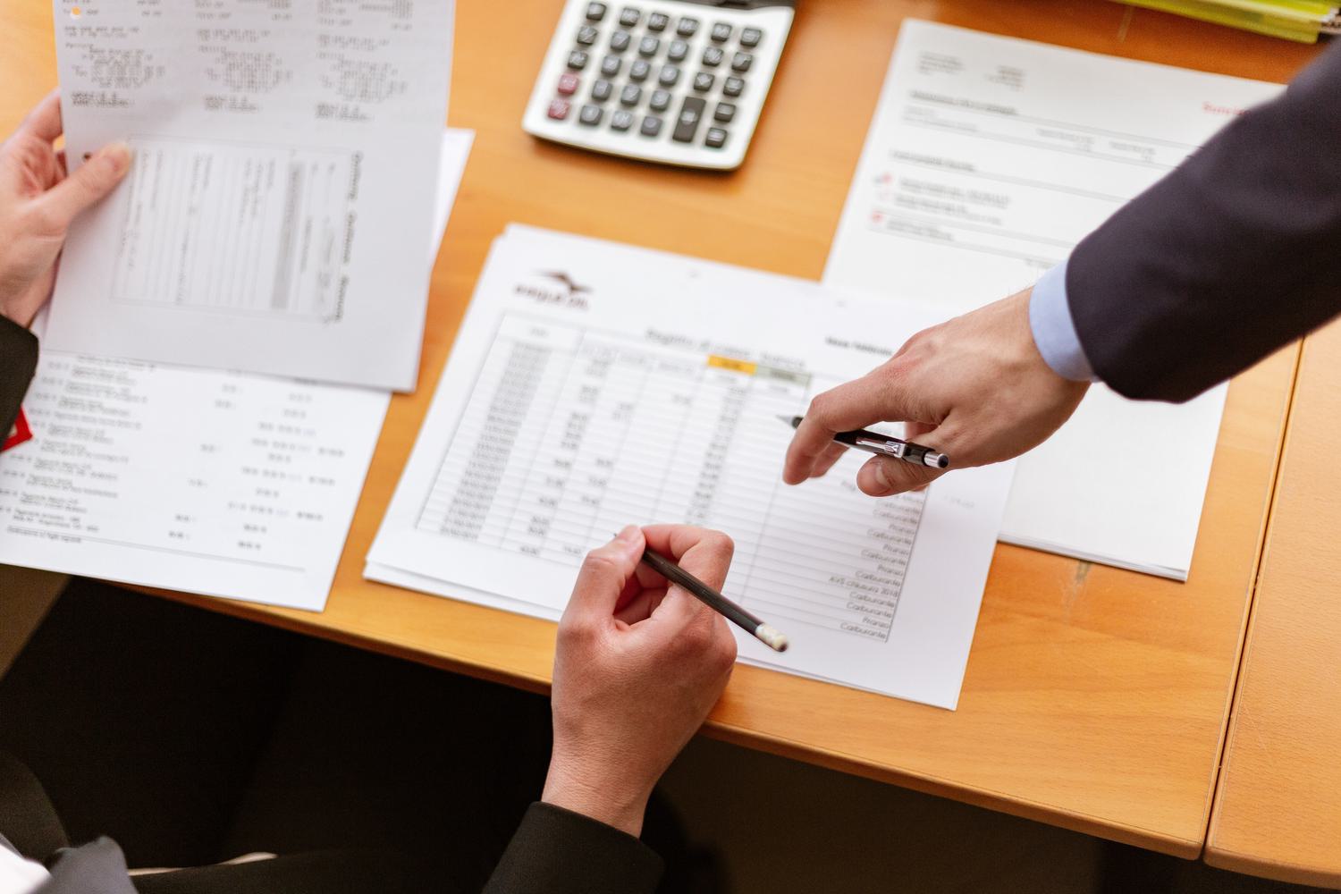 Accountant resting their hand on table with calculator and papers