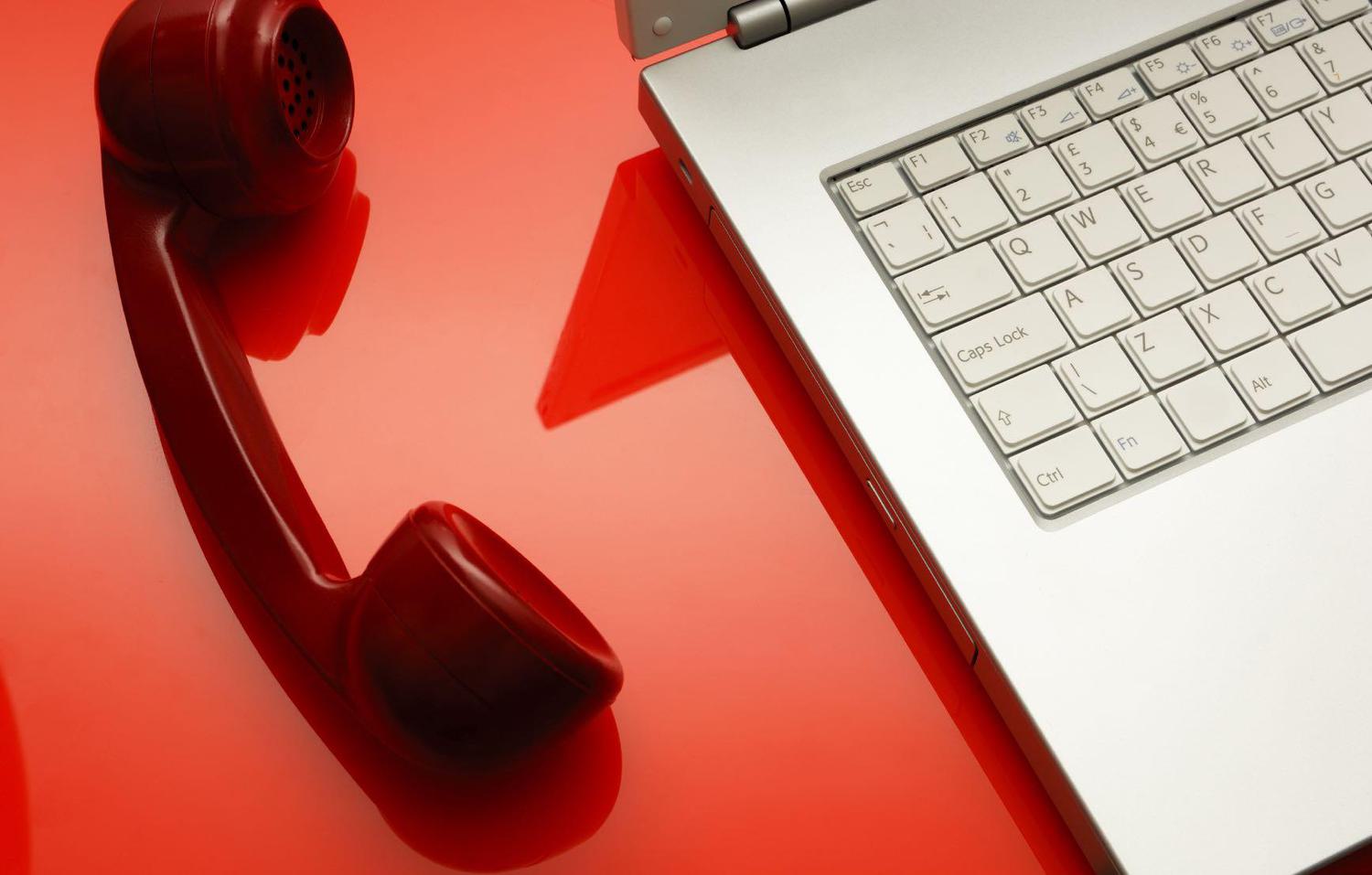 Red phone beside a laptop off the hook