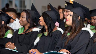 4 graduates in cap and gown from truman bodden uni
