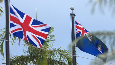 Cayman Islands and Union Jack flag on poles in between palm trees on the Cayman Islands