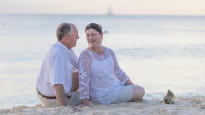 Elderly couple staring into each others eyes while sitting on the beach