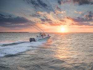 Fishing boat cruising out to sea during sunrise