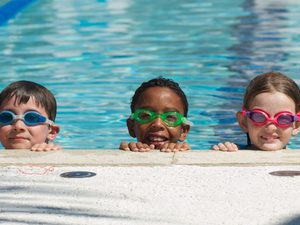 Five kids looking over the edge of large swimming pool