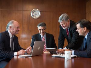 Four white businessmen sitting around a boardroom table