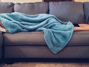 Lady on couch under blanket sick with Dengue