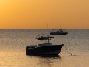 Small fishing boat anchored offshore during sunset