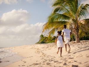 Young girl and boy dressed in white running on the beach