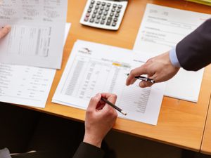 Accountant resting their hand on table with calculator and papers