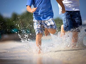 Close crop image of two little boys running through the surf