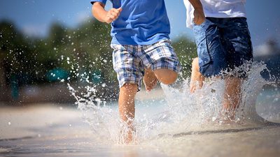 Close crop image of two little boys running through the surf