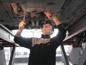 Man in black jacket and black pants standing under vehicle