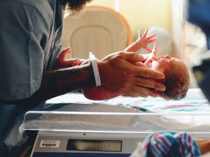 Newborn baby being weighed by a nurse