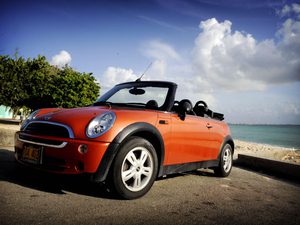 Orange mini cooper parked in front of the water