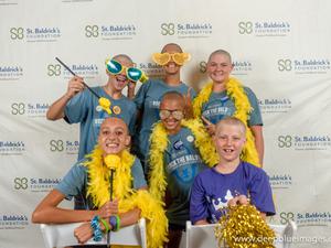 People who did the Big Shave Fundraiser for the St Baldricks foundation in front of a screen