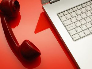 Red phone beside a laptop off the hook