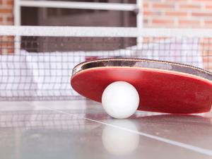 Red racquet resting on a white ping pong ball