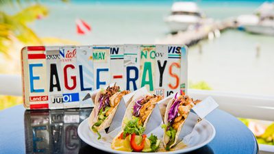 Three fish tacos sitting on table in front of ocean