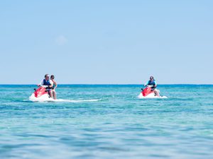 Three people enjoying the afternoon jetskiing on the beautiful blue ocean