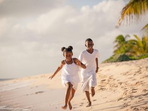 Two children running down the beach laughing