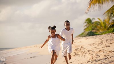 Two children running down the beach laughing