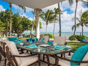 View of patio overlooking the ocean with outdoor table set for lunch